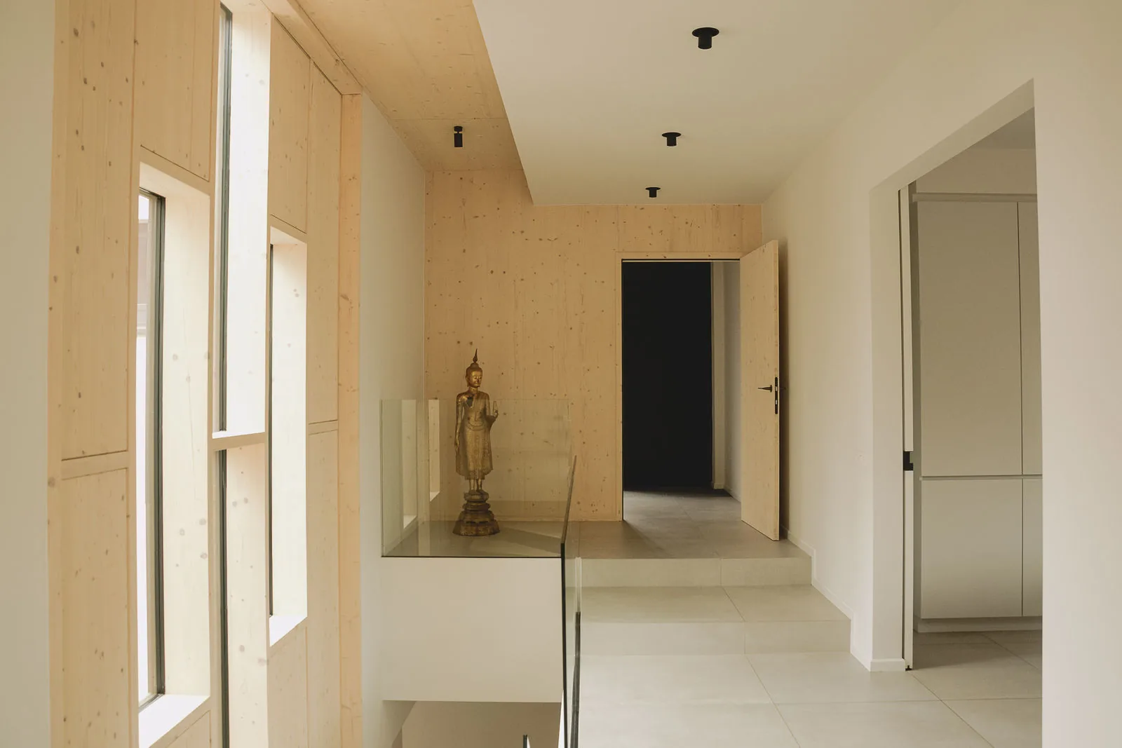 Le hall intérieur : murs et plafond en CLT apparent, sol clair, porte laissée brute