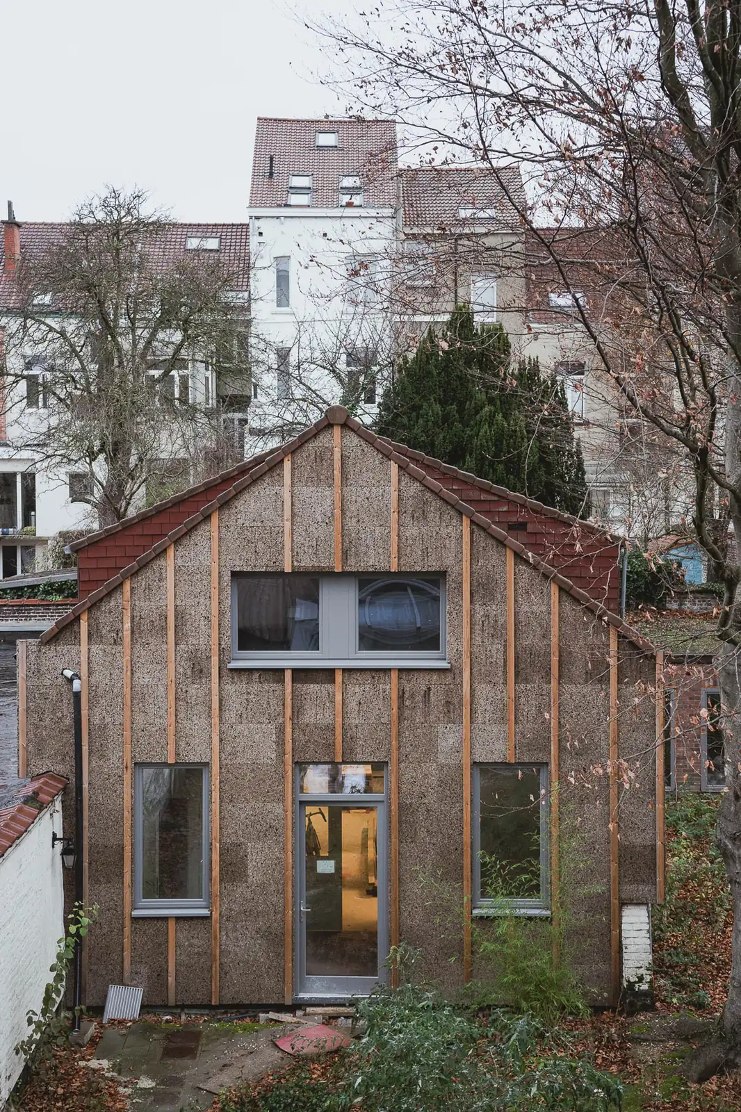 La façade du bâtiment secondaire, entièrement parée de panneaux de liège expansé apparent entre des tasseaux de bois