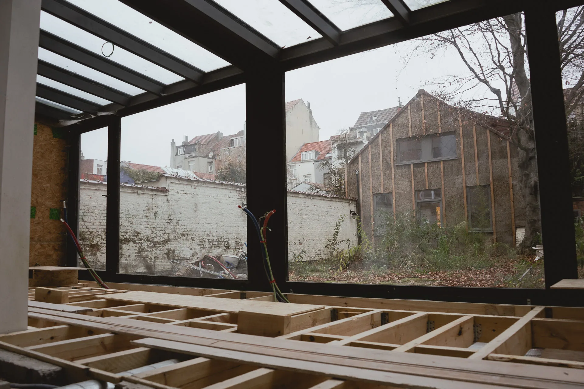 Vue depuis l'intérieur en chantier vers la cour, le bâtiment secondaire paré de liège expansé au fond