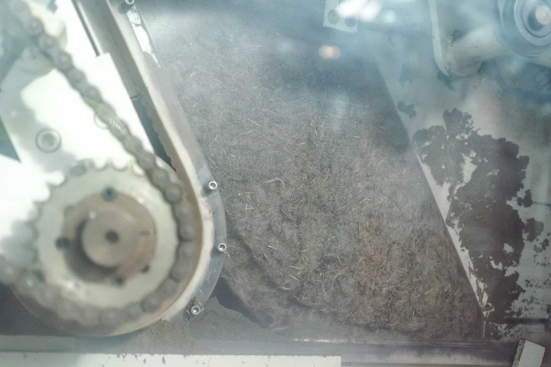 Les fibres d'herbe dans la machine d'ouverture, vues à travers la vitre de la ligne