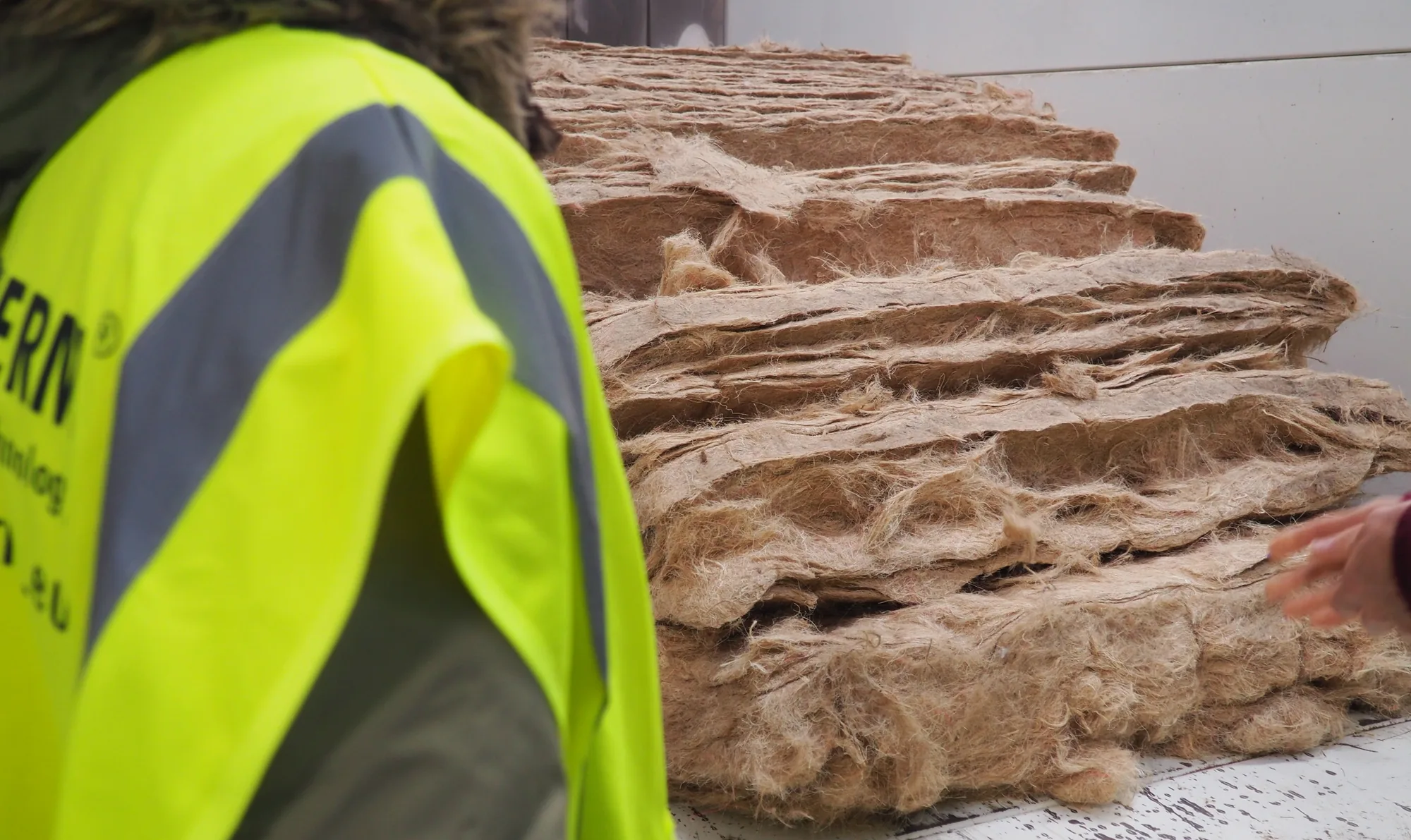 Panneaux de fibre d'herbe empilés à la sortie de ligne, un opérateur en gilet au premier plan