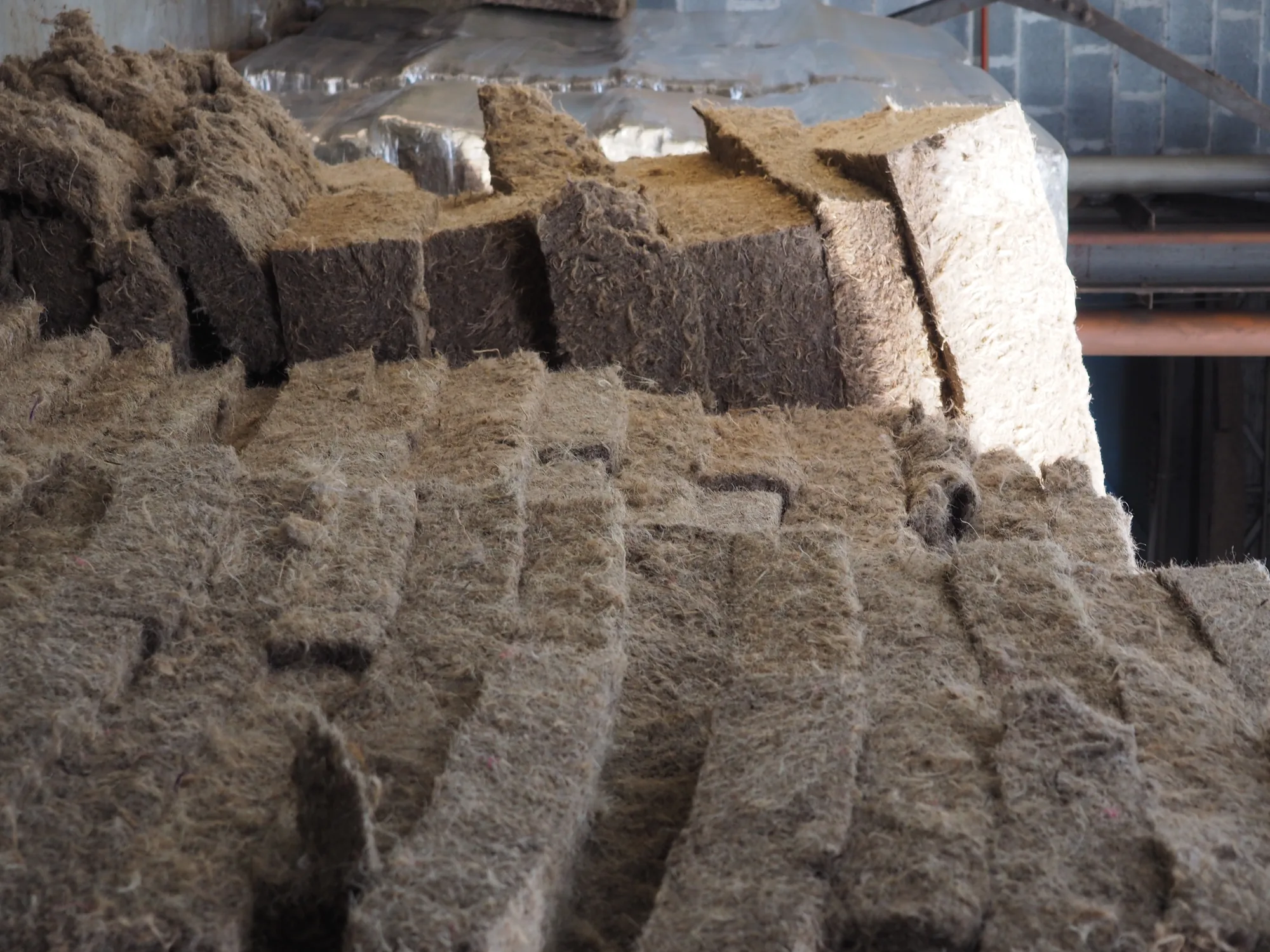 Pile de panneaux de fibre d'herbe vue en biais, épaisseurs et densités visibles sur la tranche