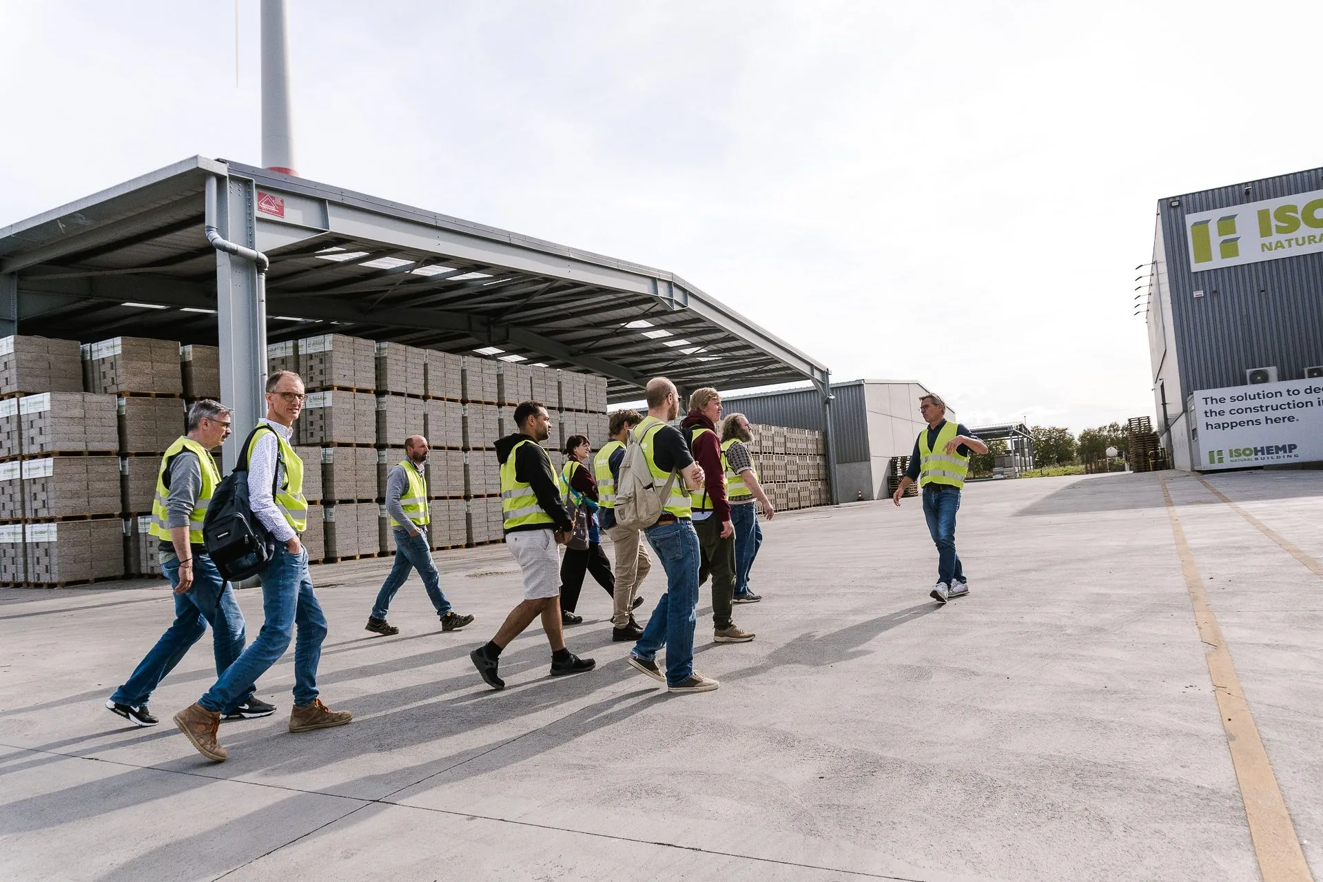 Architectes et entrepreneurs traversent la cour de l'usine IsoHemp, guidés vers les halls