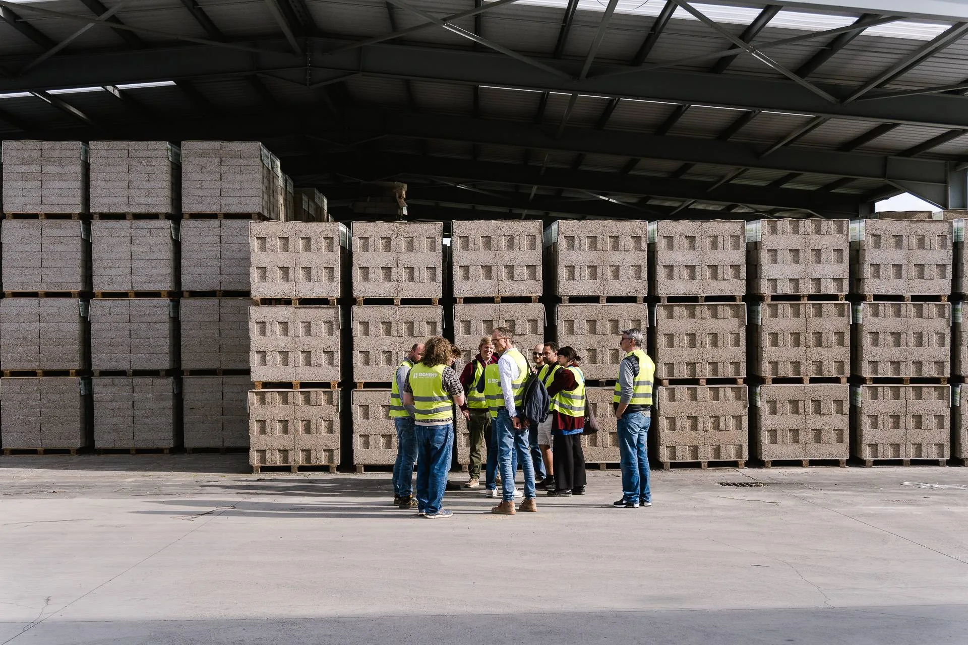 Le groupe rassemblé devant les palettes de blocs de chanvre stockées sous l'auvent de l'usine IsoHemp