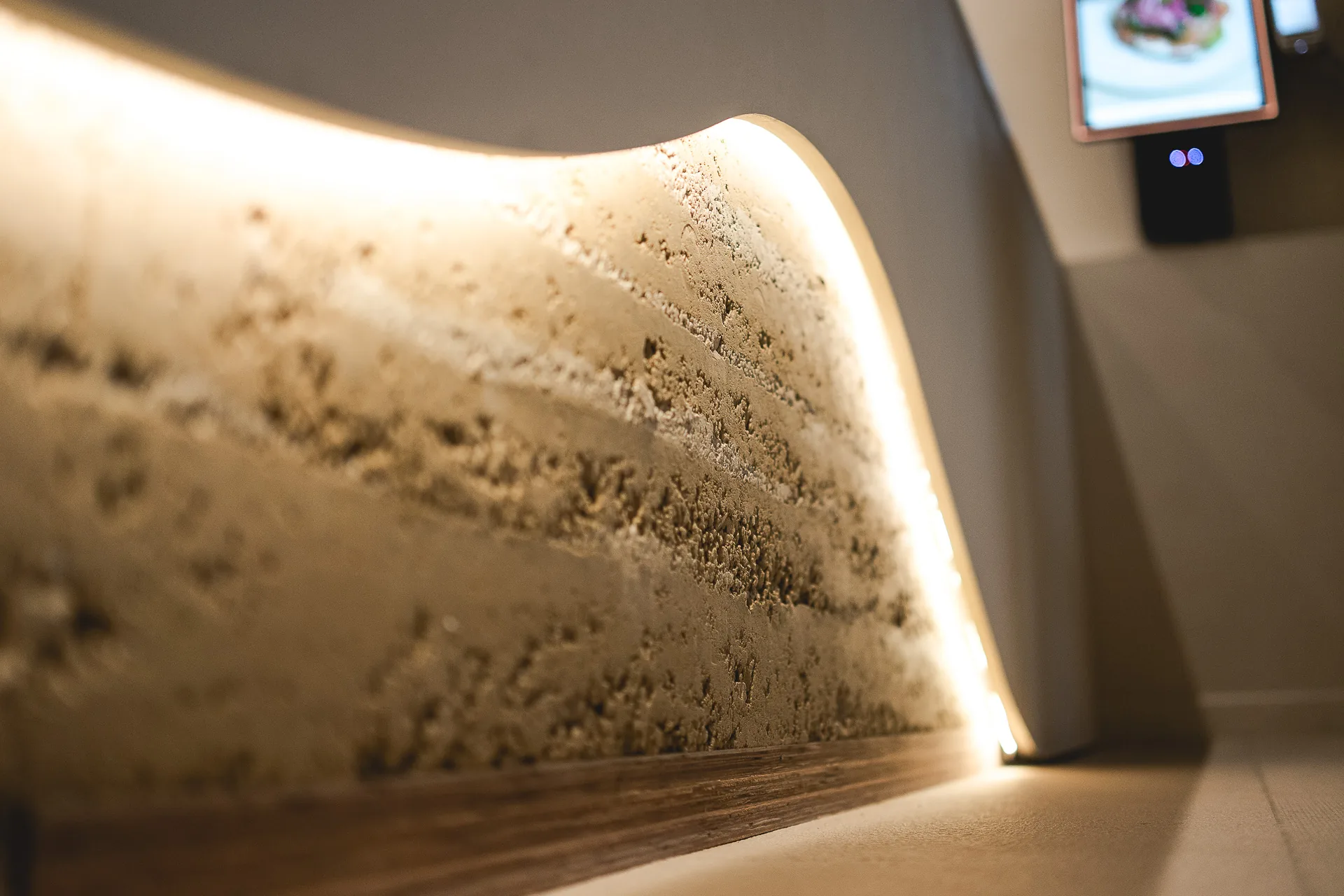 La banquette en rammed earth en lumière rasante, les levées de terre lisibles sur toute sa longueur