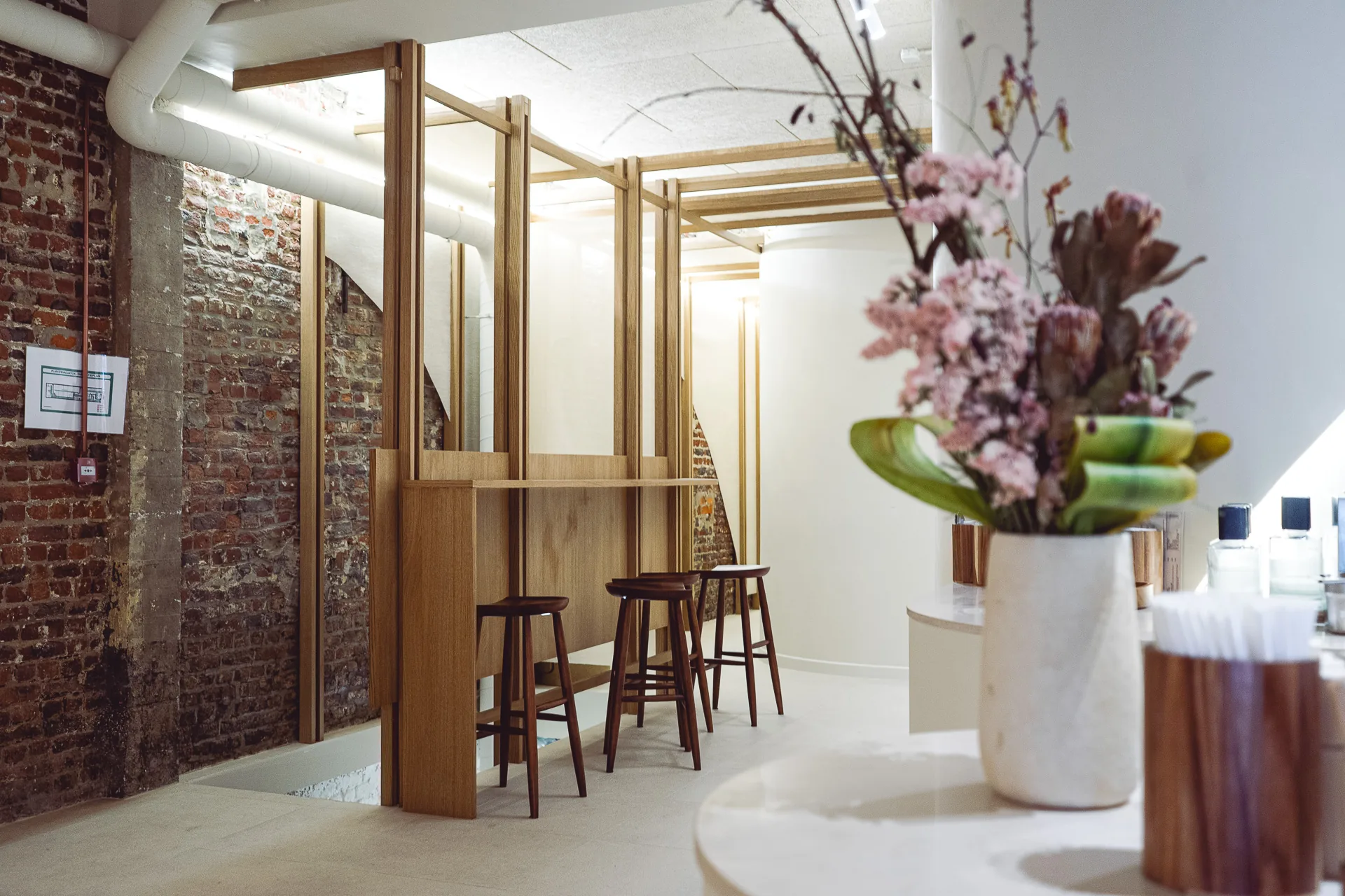 L'espace café, tasseaux de bois et mur de brique conservé, un bouquet sur le comptoir