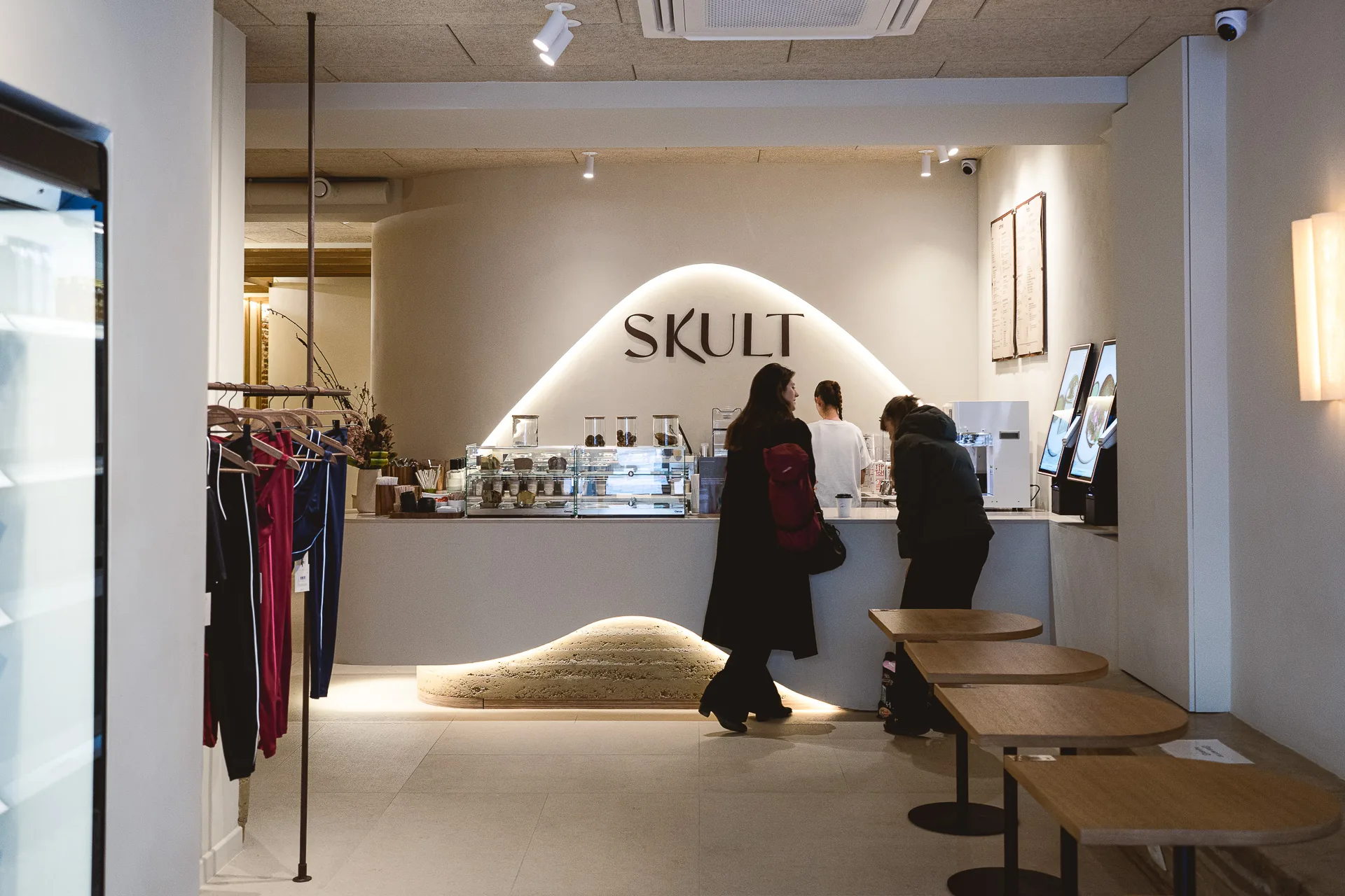 La salle principale, l'enseigne SKULT au mur et la banquette de terre qui court sous les tables