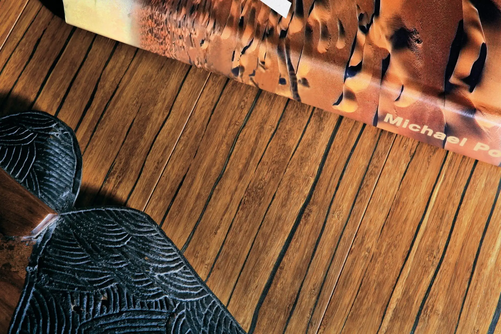 Gros plan rasant sur les lames du parquet bambou BamWood Nairobi (bambou thermotraité, teinte brun foncé) : fibres longitudinales, nœuds de croissance et joints de lames lisibles.