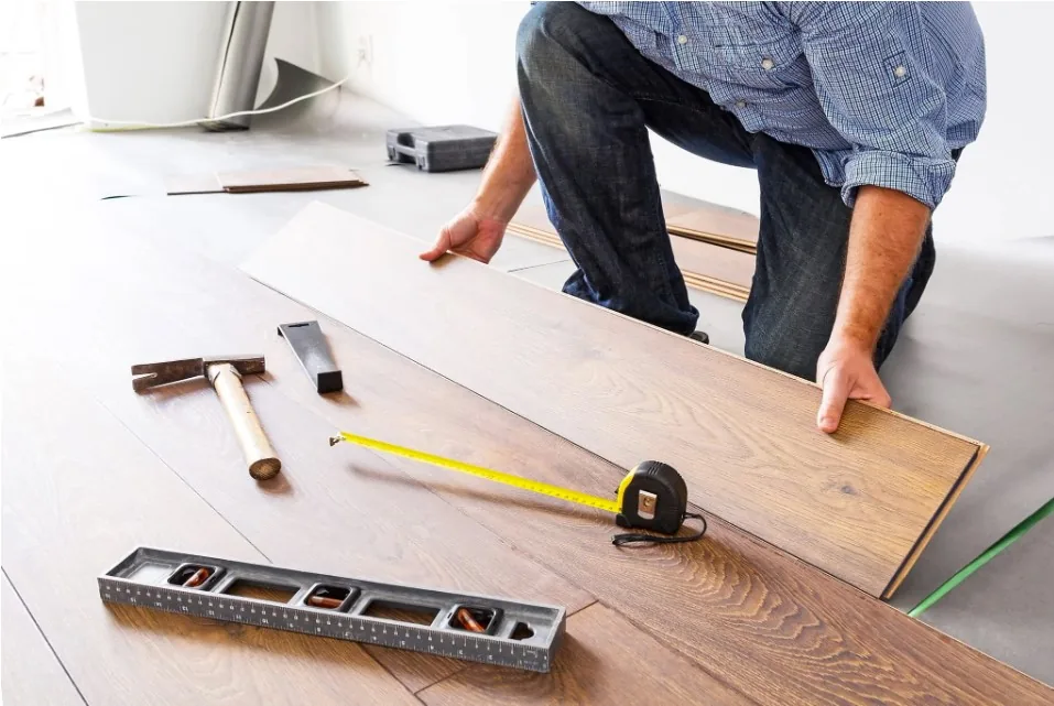 Pose d'une lame de parquet en bambou, mètre ruban et outils au sol