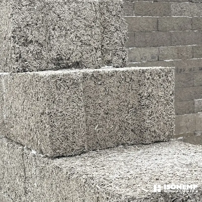 Gros plan sur deux blocs de chanvre poses en angle d'arase : arete nette, epaisseur et granulometrie du bloc parfaitement lisibles (chantier d'Annezin)