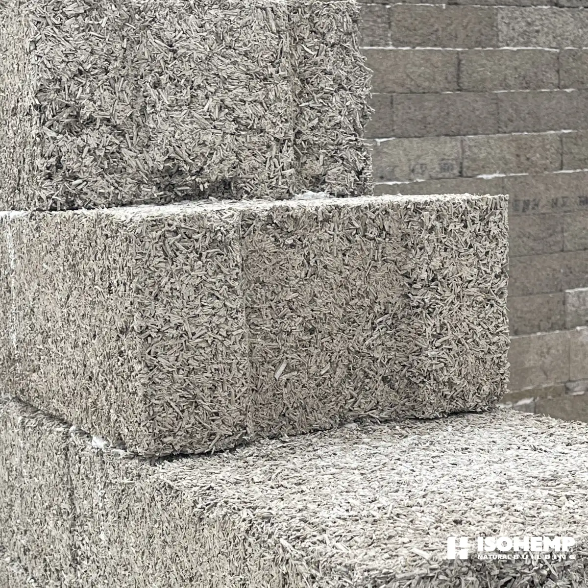 Gros plan sur deux blocs de chanvre poses en angle d'arase : arete nette, epaisseur et granulometrie du bloc parfaitement lisibles (chantier d'Annezin)