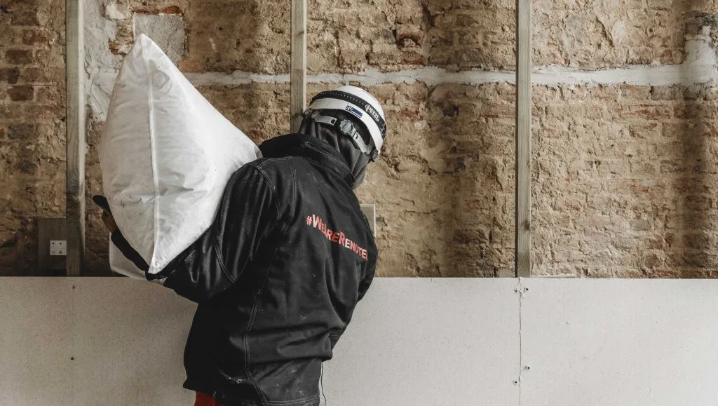 Chantier château de Boekenberg (Renotec) : ouvrier portant un sac de CaNaDry devant le mur à ossature bois en cours de remplissage
