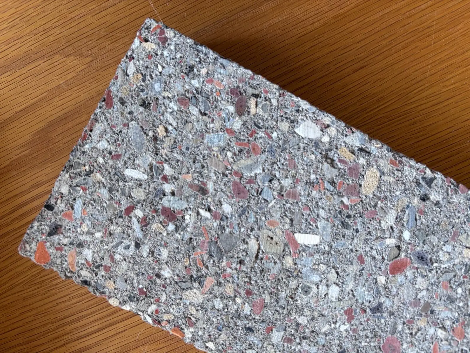bloc clayton.jpg — échantillon de bloc Clayton posé sur un plan de travail : granulats de démolition recyclés (brique rouge, terre cuite, pierre) bien visibles