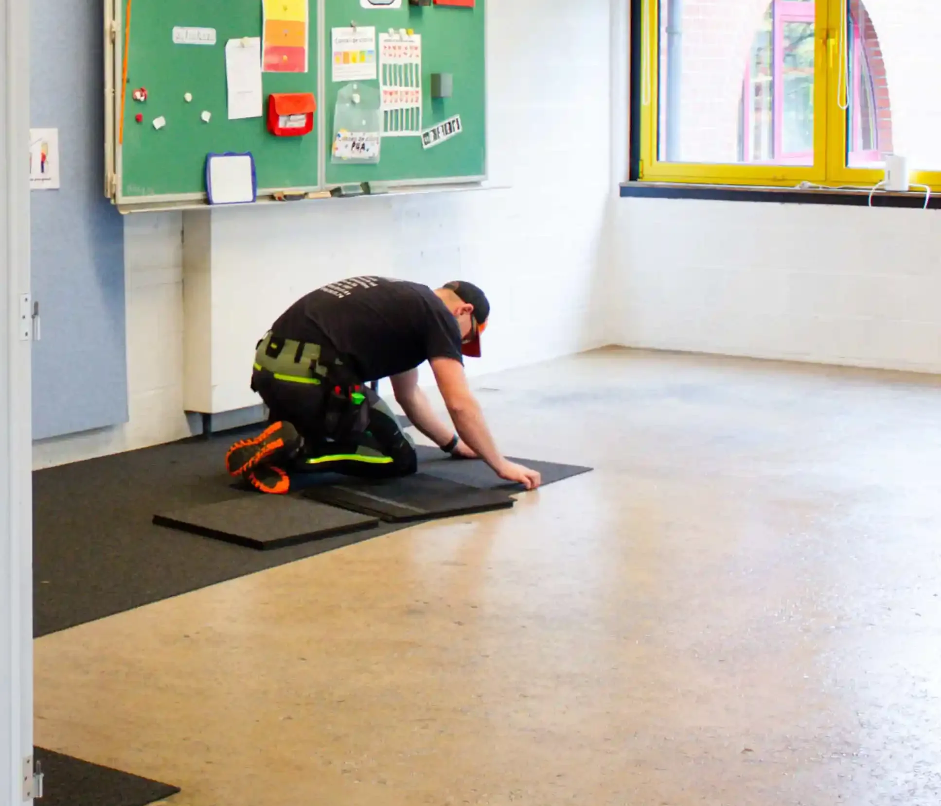 Kneeling installer adjusting a carpet tile on a bare screed