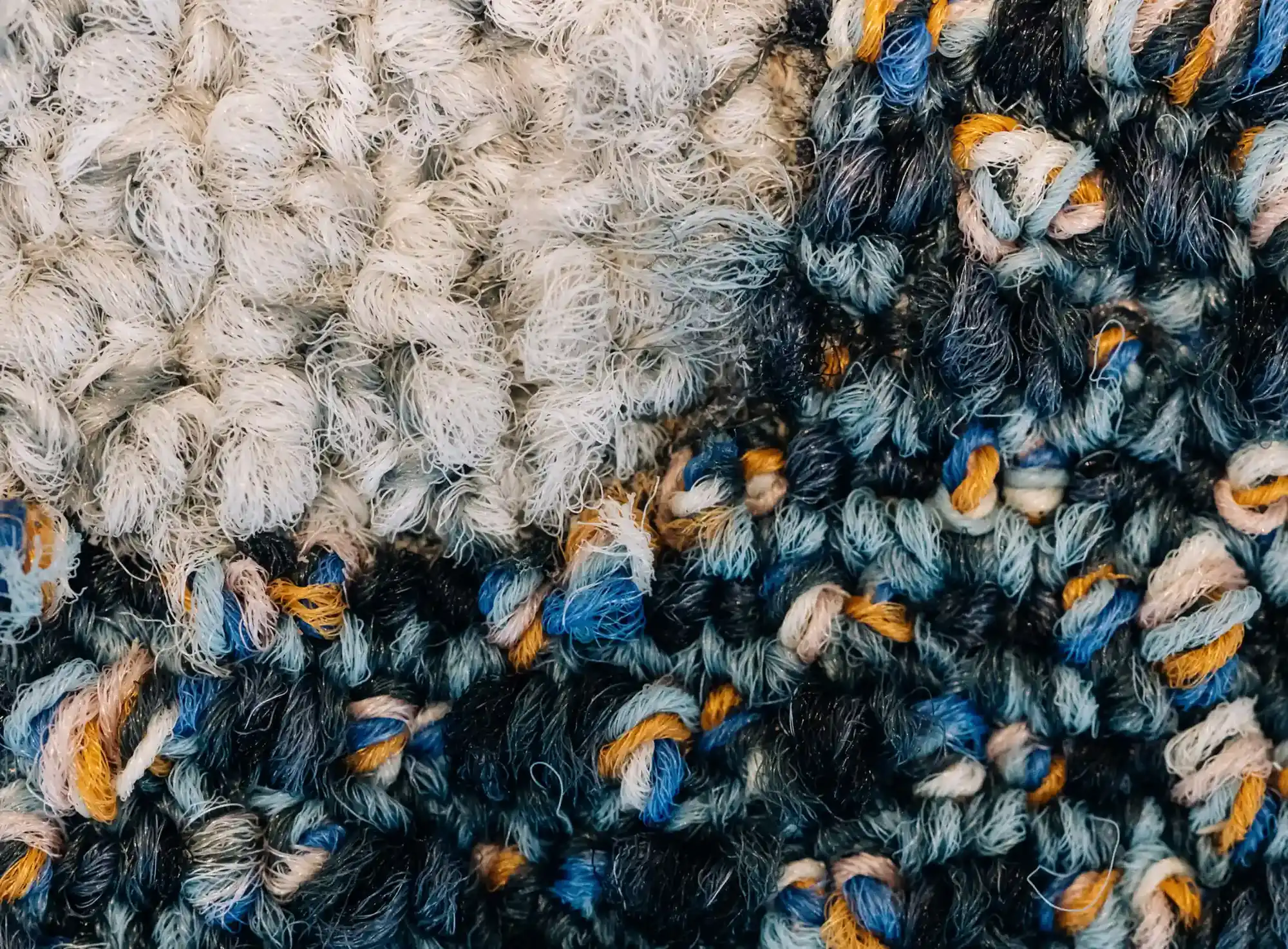 Loop pile of two adjoining reclaimed carpet tiles, in close-up
