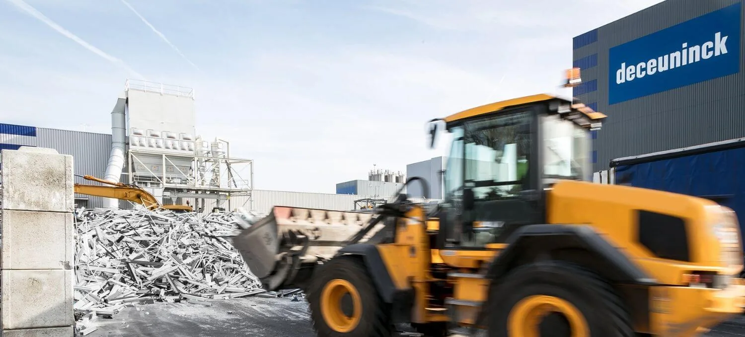 Loader picking up a heap of old PVC profiles in front of the Deceuninck plant