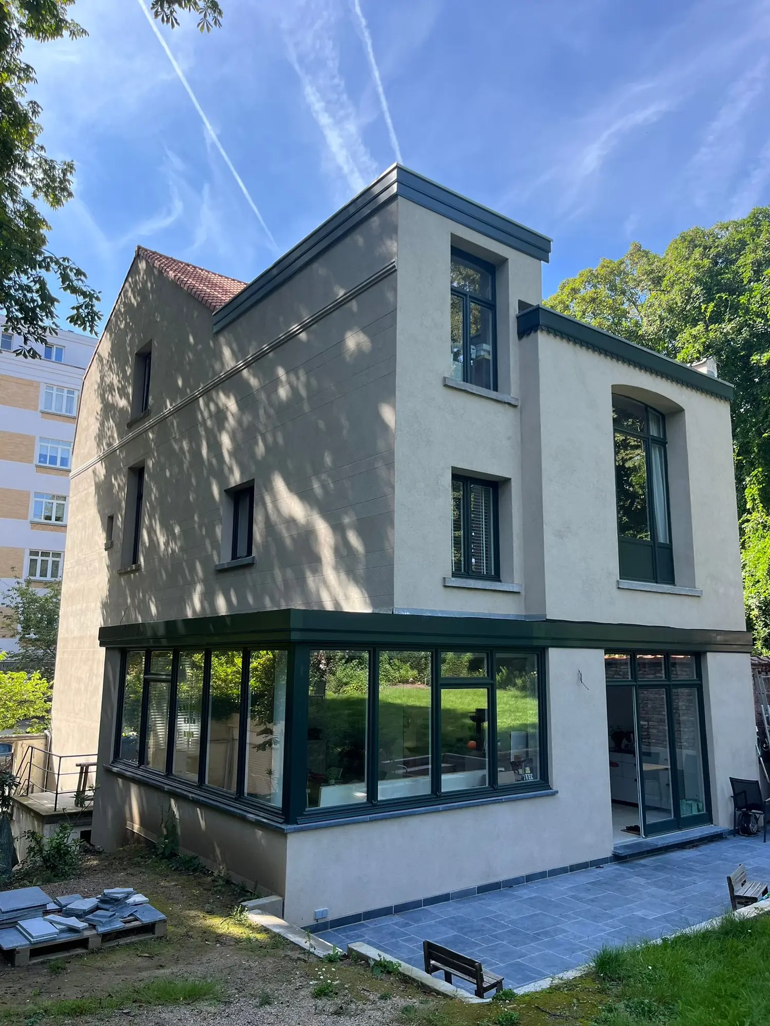 Façade d'une maison contemporaine enduite à la chaux, menuiseries sombres