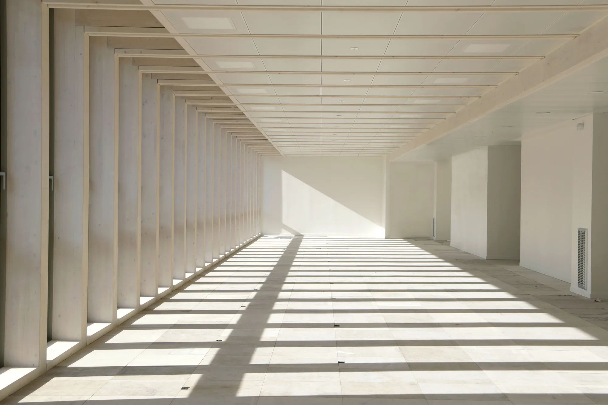 Couloir de bureaux en plancher technique de réemploi, lumière traversante