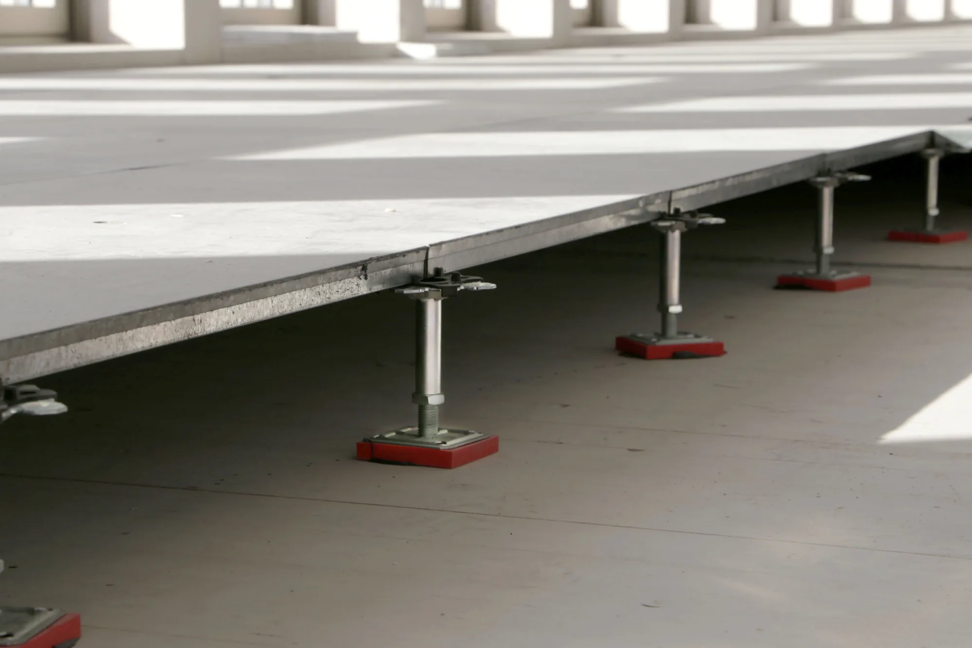 Plots réglables et dalles de faux-plancher en cours de montage