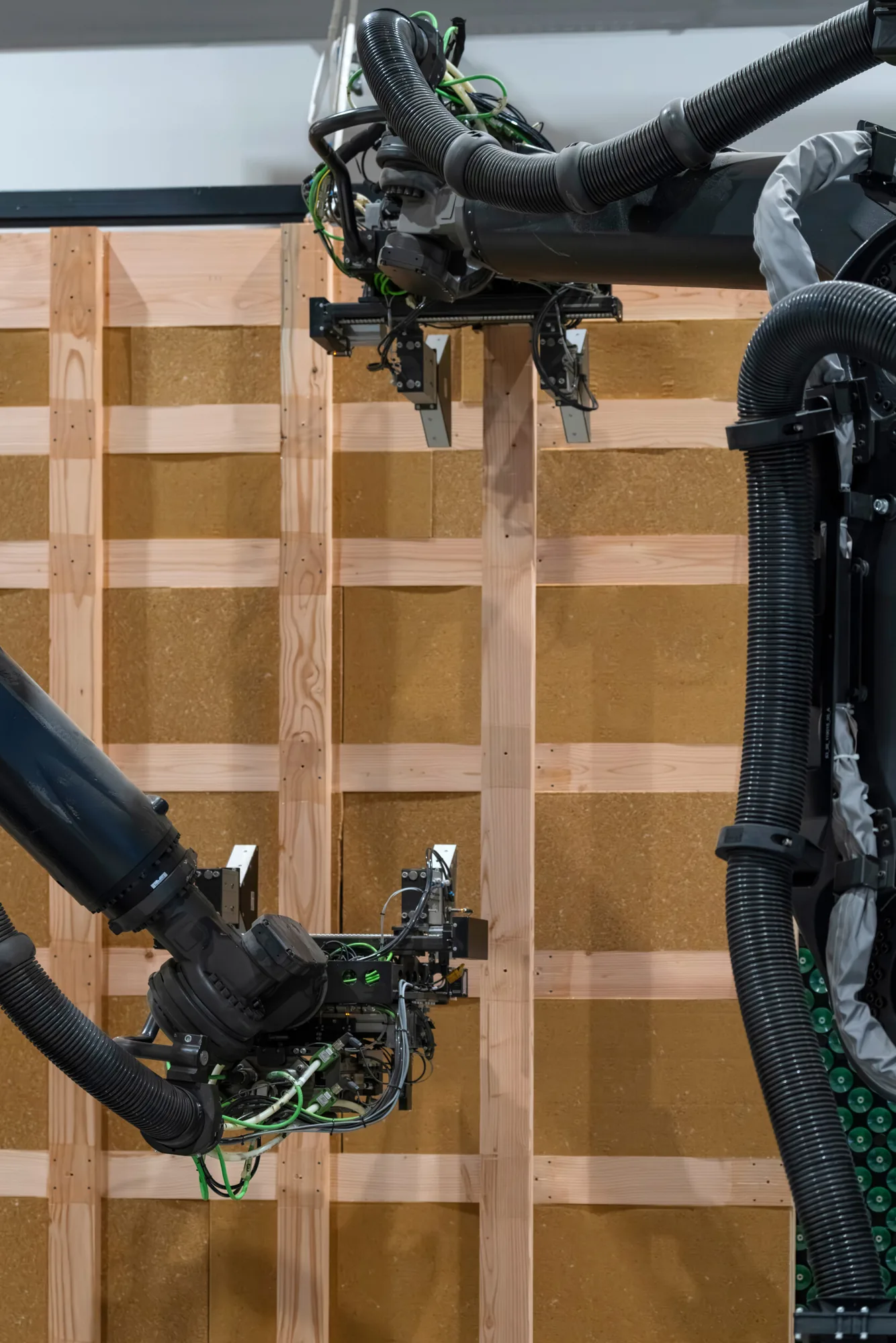 LEKO Lattice wall being fabricated, timber studs and wood fibre boards, robotic arms in the foreground
