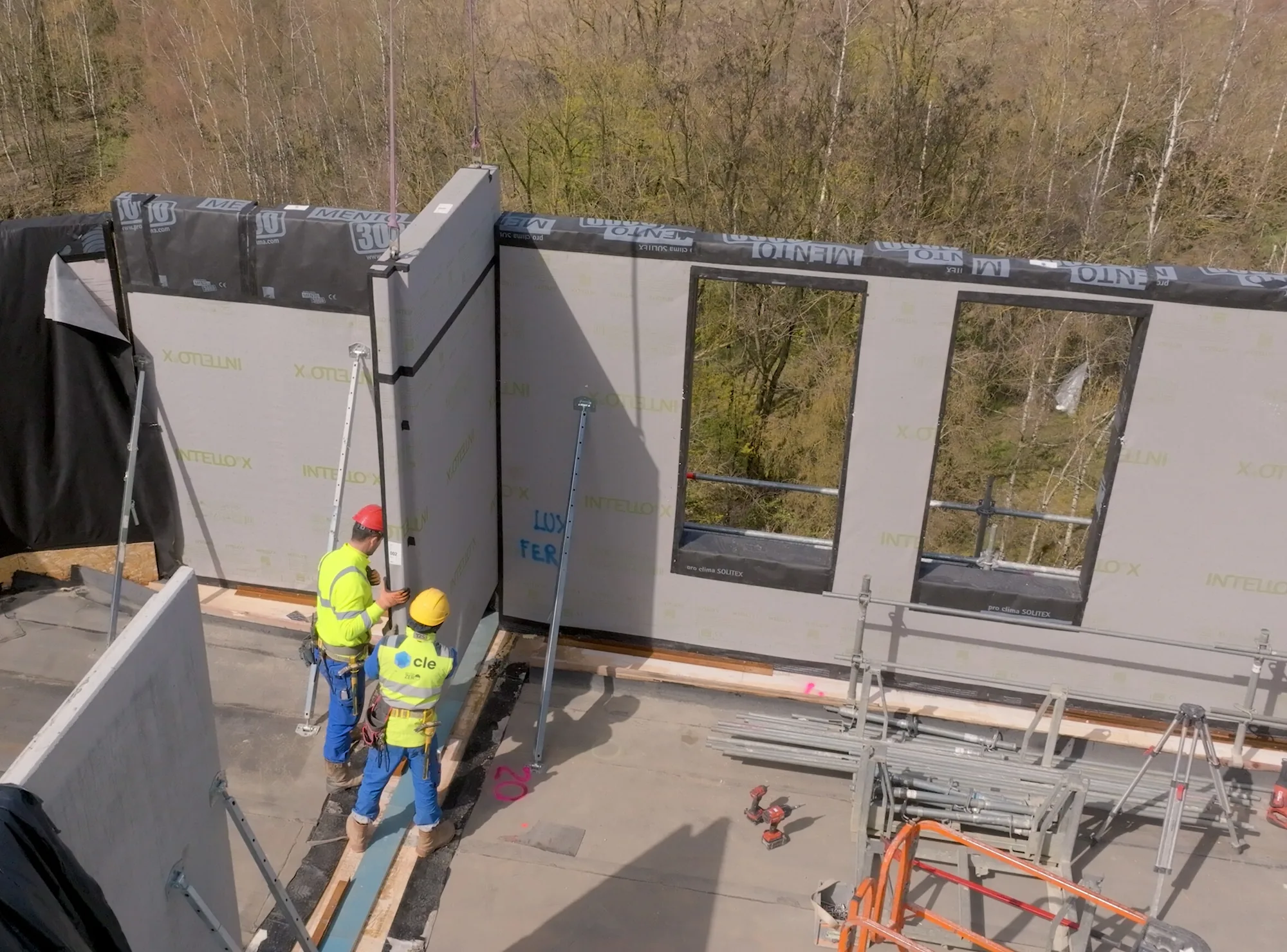 Two workers propping a prefabricated wall panel as it is installed on a floor