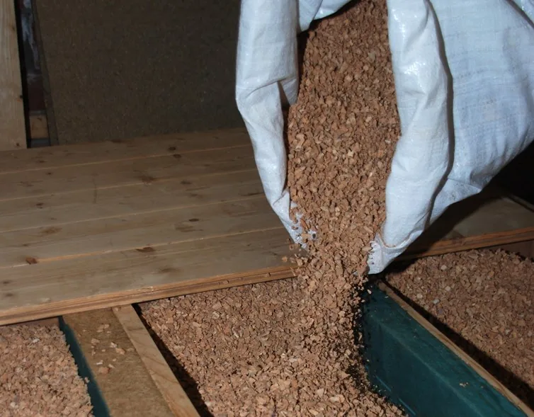 Granulés de liège Recycork épandus entre solives, sacs au sol