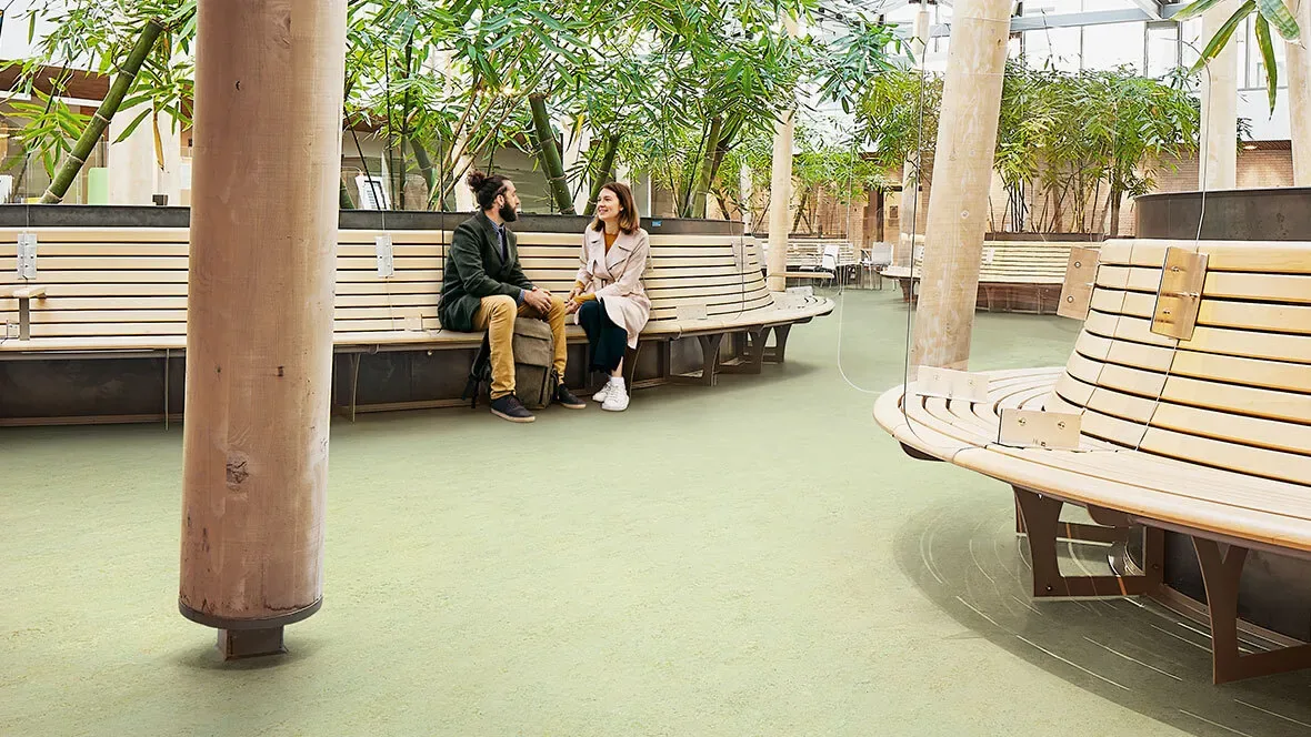Marmoleum Topshield Pro — grand hall planté, sol Marmoleum vert olive en premier plan, texture marbrée lisible