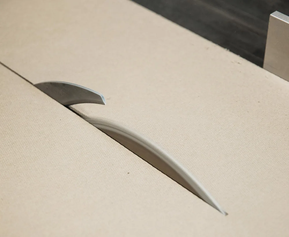 Detail de decoupe : lame de scie circulaire traversant un panneau HONEXT, coeur du materiau visible dans le trait de scie