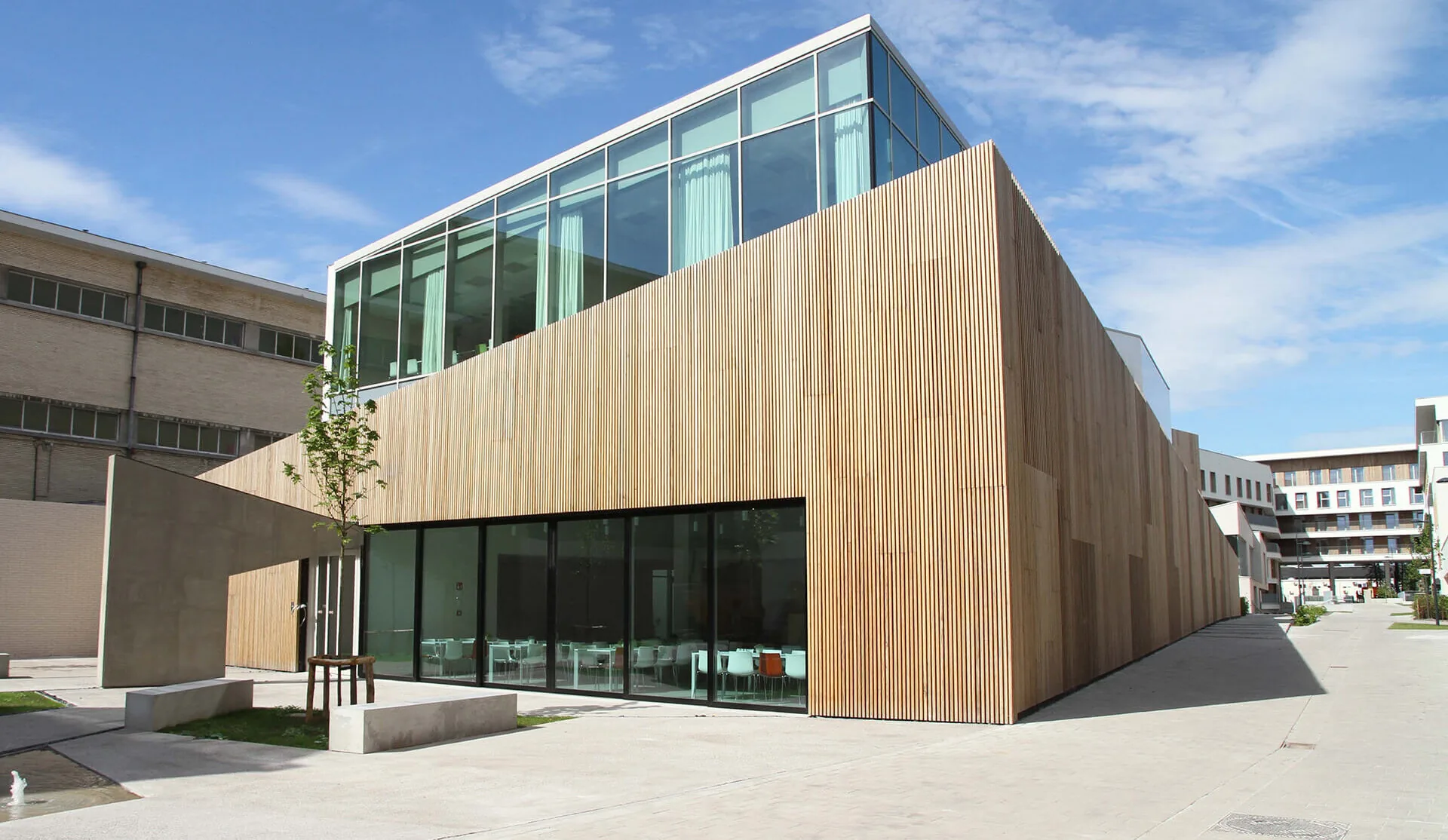 Building with vertical platonised frake cladding, glazed storey set back