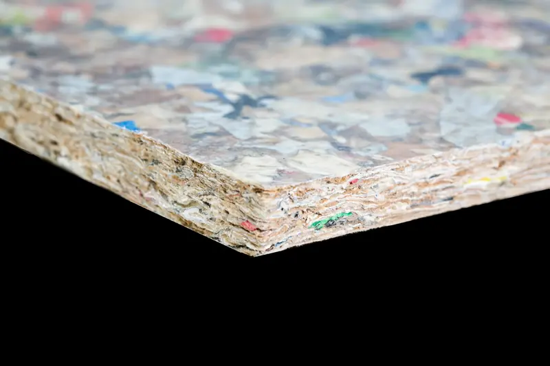 Panneau PackWall Design de Recoma, prise de vue studio sur fond neutre : le moucheté polychrome caractéristique (éclats de plastique et d'aluminium des briques alimentaires) et la tranche feuilletée sont nets et lisibles dès la vignette. © Recoma AB