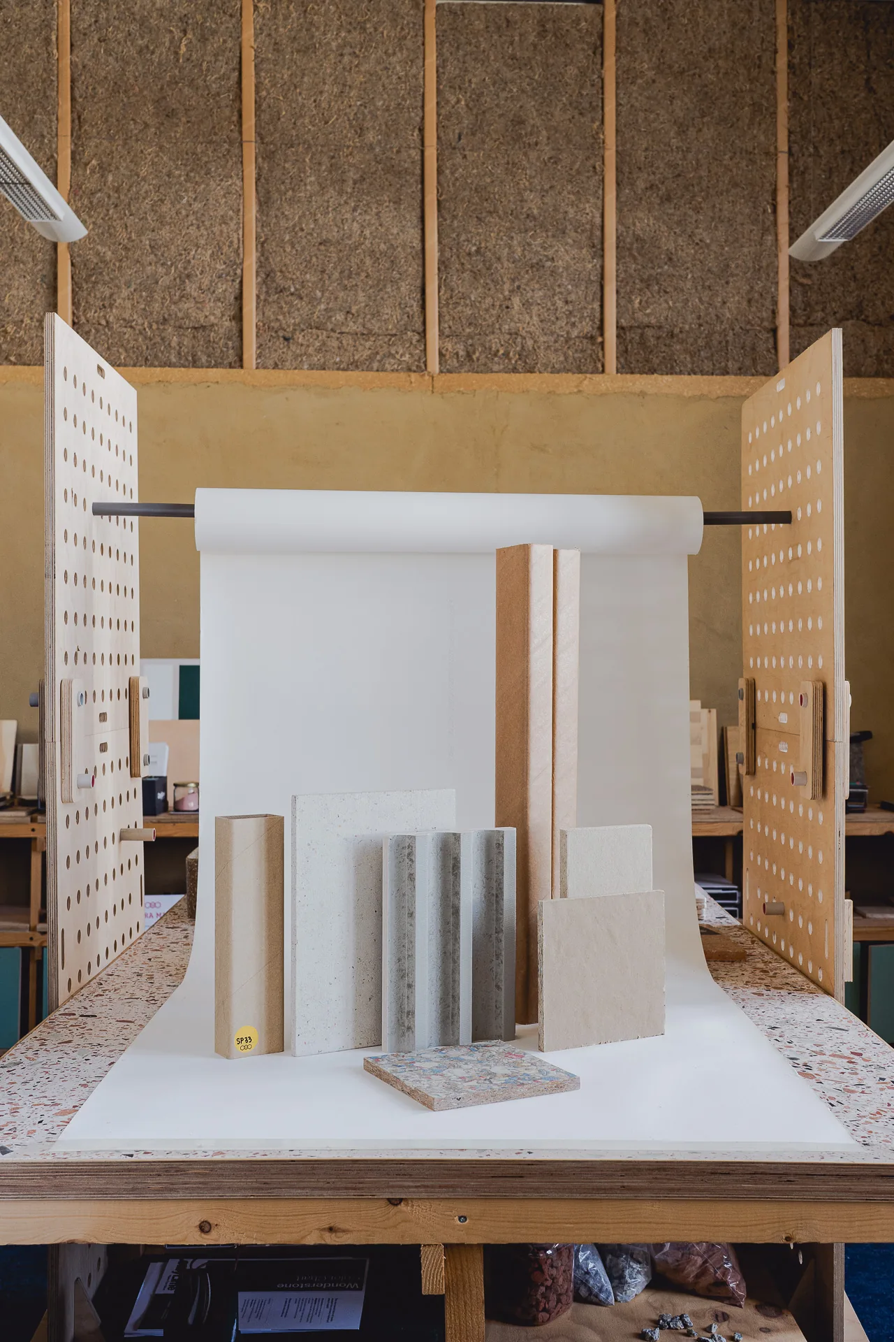 Panel samples standing on the photography table at the Materatek, in front of a wall of fibre insulation between timber studs